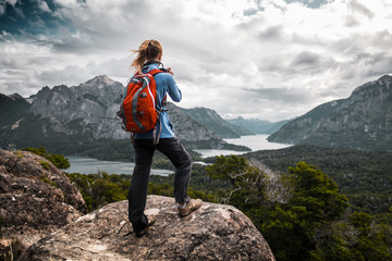 Tourist hiker with red backpack takes pictures of the valley with mountains and lakes. Patagonia,...