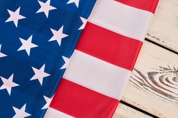 National flag of USA on white wood. Flag of United States of America folds on white wooden background. Symbol of USA.