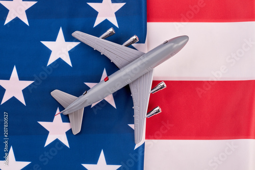 American flag background and grey toy air plane. Plastic toy jet plane and national flag of United States of America. Trip to USA.