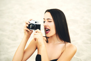 Young cheerful woman taking photos with retro camera