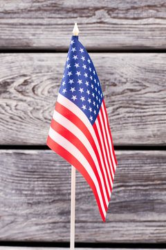 National flag of USA, vertical image. Small flag of United States of America on old wooden background. Symbol of nation and patriotism.