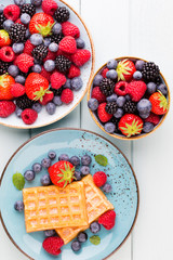 Fresh berry salad on blue dishes. Vintage wooden background.