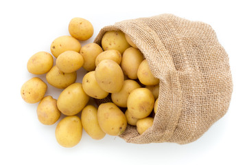 Sack of fresh raw potatoes on wooden background, top view