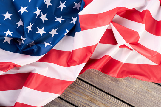 Close up crumpled flag of the USA. National flag of United States of America on light wooden background.