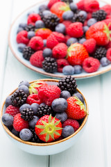 Fresh berry salad on blue dishes. Vintage wooden background.