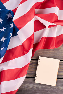 USA flag and opened notebook, top view. Flag of America and personal organizer book on wooden background, vertical image.