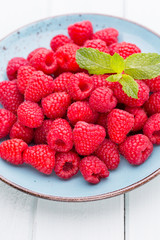 Fresh raspberries in a plate on a  vintage background.