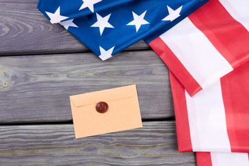 Craft envelope and American flag. USA flag folded on wooden background, top view. Greeting with Independence Day.