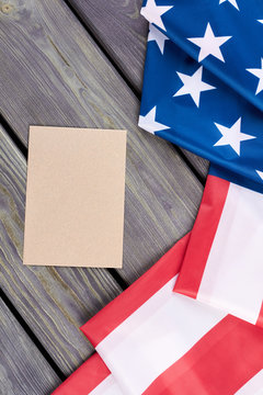 USA flag and craft envelope, top view. Flag of United States of America and brown envelope on wooden background, vertical image.