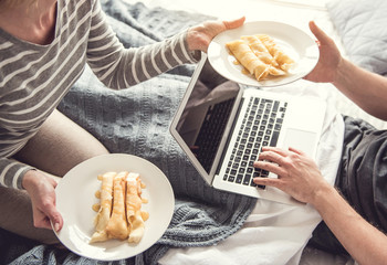 Top view of caring woman holding two plates with pancake and offering meals to man. Boyfriend is...