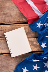 USA flag and notepad, vertical image. Crumpled flag of America and notebook on old wooden boards.