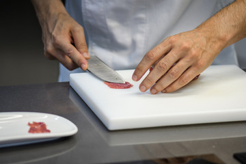 young chef cutting meat