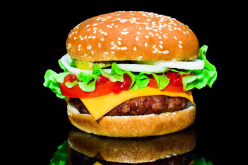 Big tasty hamburger or cheeseburger on black background with grilled meat, cheese, tomato, bacon, onion. Burger closeup