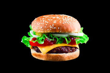 Big tasty hamburger or cheeseburger isolated on black background with grilled meat, cheese, tomato, bacon, onion. Burger closeup