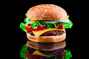 Big tasty hamburger or cheeseburger on black background with grilled meat, cheese, tomato, bacon, onion. Burger closeup