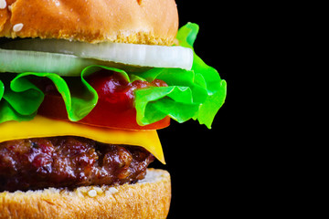 Big tasty hamburger or cheeseburger on black background with grilled meat, cheese, tomato, bacon, onion. Burger closeup