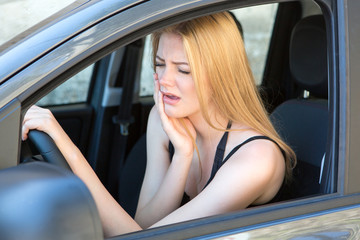 Fototapeta na wymiar blond woman having toothache while driving car