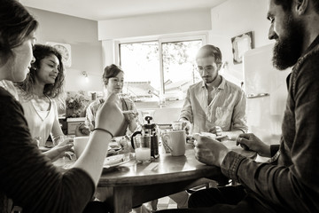 bunch of multi-ethnic friends gathered around a table for breakf