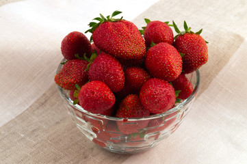 Glass round plate, filled to the top with a ripe red strawberry.