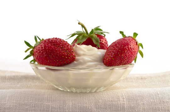 A small glass plate was laid with sour cream and a ripe strawberry.