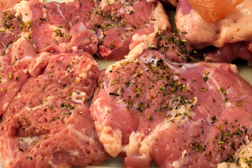 Slices of meat, sprinkled with shredded herbs, prepared to make a meat dish.