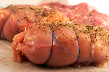 The process of making a meatloaf, the stage of pulling the rolled pieces of meat with a blue thread...