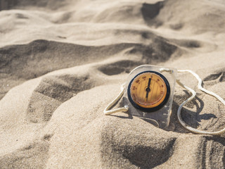 summer travel concept, compass in sand on a sea beach