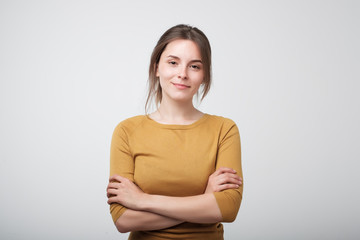 Portrait of young caucasian woman in yellow shirt casually standing near gray wall. Concept of...