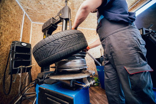 Professional car mechanic replace tire on wheel.