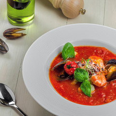 High class healthy Italian meal on a table. Tomato soup with seafood in a plate.