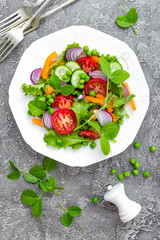 Salad. Fresh vegetable salad with tomato, onion, cucumbers, pepper, lettuce and green peas. Vegetarian salad with vegetables on plate