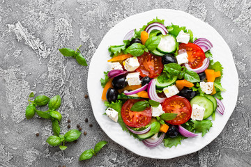 Greek salad. Fresh vegetable salad with tomato, onion, cucumbers, basil, pepper, olives, lettuce and feta cheese. Greek salad on plate