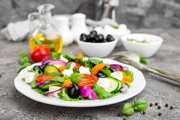 Greek salad. Fresh vegetable salad with tomato, onion, cucumbers, basil, pepper, olives, lettuce and feta cheese. Greek salad on plate