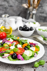 Greek salad. Fresh vegetable salad with tomato, onion, cucumbers, basil, pepper, olives, lettuce and feta cheese. Greek salad on plate
