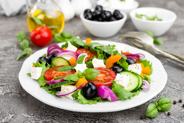 Greek salad. Fresh vegetable salad with tomato, onion, cucumbers, basil, pepper, olives, lettuce and feta cheese. Greek salad on plate