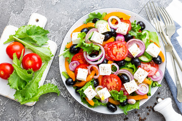 Greek salad. Fresh vegetable salad with tomato, onion, cucumbers, pepper, olives, lettuce and feta cheese. Greek salad on plate