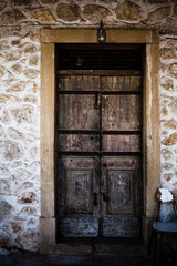 An old ancient wooden door in stones background in Corfu Greece. Antique castle entrance in rocks wall and frame made of wood. Beautiful vintage architecture