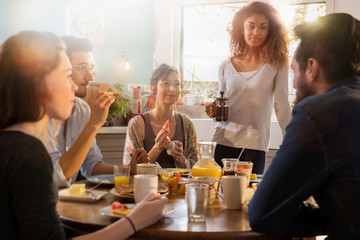 bunch of multi-ethnic friends gathered around a table for breakf