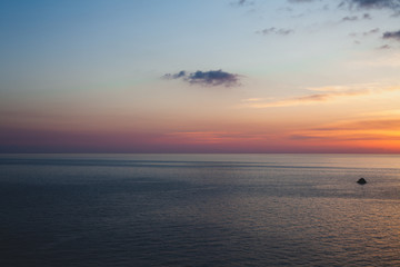 Sunset at the beach with some clouds in the sky. Blue and pink shades with dark clouds. Quiet place. Relaxing scene of beaches. Beautiful natural landscape. Peaceful view