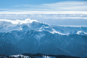Fototapeta na wymiar High mountains, lots of white pure snow and clouds lie on the mountains in Sochi, Russia