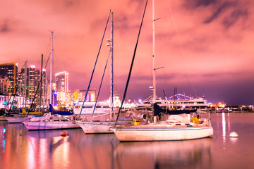Beautiful San Diego California at night after sunset with pink sky, skyline buildings, boats and...