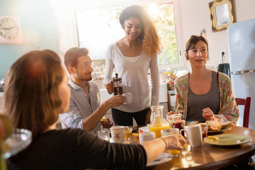 bunch of multi-ethnic friends gathered around a table for breakf