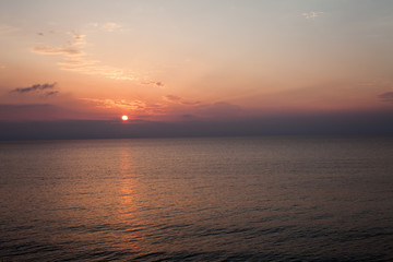 Sunset at the beach with some clouds in sky. Blue and pink shades with dark clouds. Quiet place. Relaxing scene of beaches. Beautiful natural landscape. Peaceful view