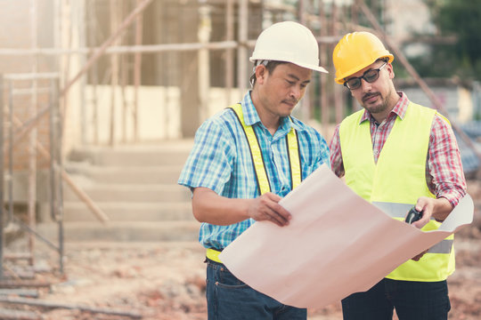 Male engineer talking with worker at a construction site.