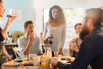 bunch of multi-ethnic friends gathered around a table for breakf