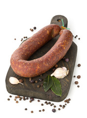 German specialty salami hard cured sausage whole with spices on wooden board