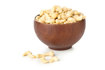 Heap of raw, organic, whole cashew nut kernels in wooden bowl over white