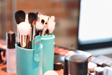 Make up artist tools ready to use with natural light in the background. Display of brushes inside blue holder
