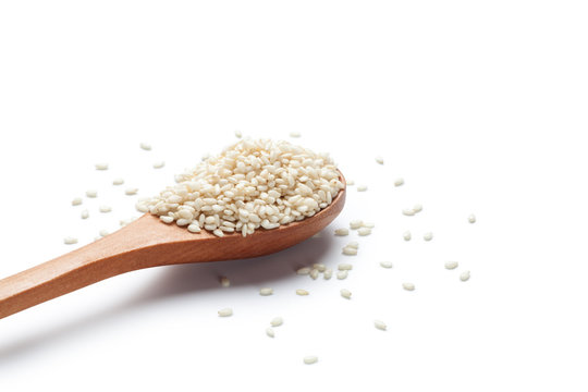 White sesame seeds in a wooden spoon on white background
