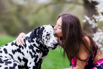 young woman gives her Dalmatian dog a kiss